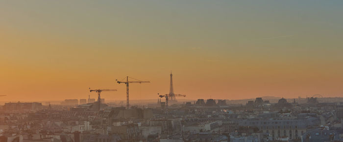 Aerial view of buildings in city against orange sky