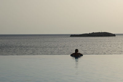 Rear view of man in sea against clear sky
