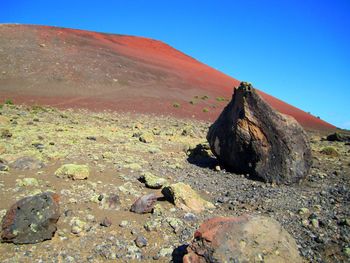 Rocks on arid landscape against clear blue sky