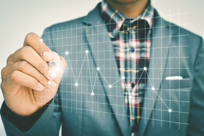 Digital composite image of businessman drawing line graph against white background