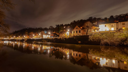 River by illuminated buildings against sky at night