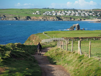 Rear view of man walking on road by river