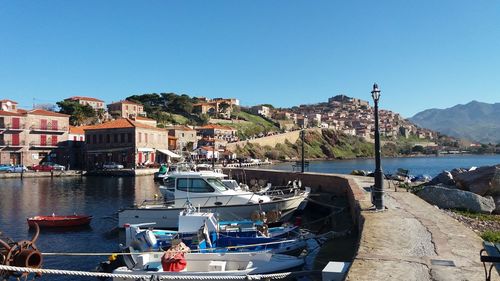 Boats moored at harbor against clear blue sky