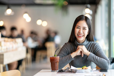 Portrait of a smiling young woman sitting at restaurant