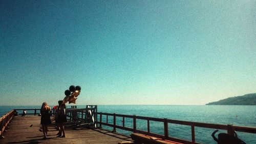 People standing on railing against sea