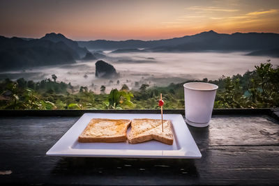 High angle view of breakfast on table against mountains during sunset