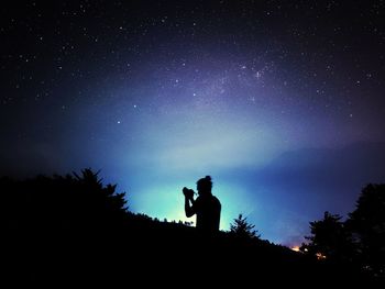 Silhouette man standing against sky at night