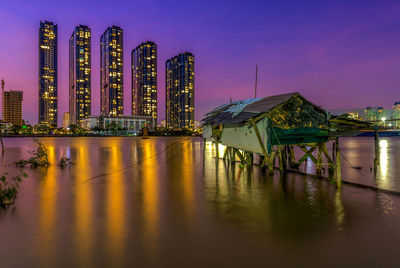 Panoramic view of illuminated pier by river against sky at night