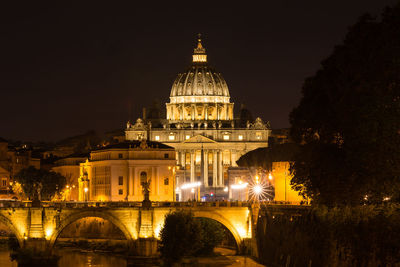 Illuminated building and arch bridge against sky at night