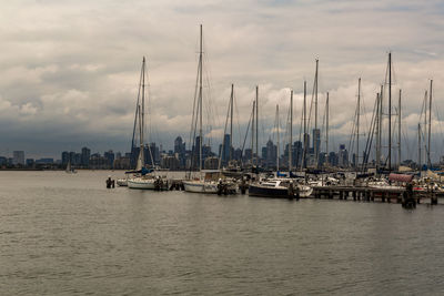 Sailboats moored in harbor against sky