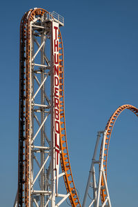 Low angle view of ferris wheel against clear blue sky