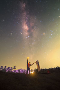 Rear view of woman standing on field at night