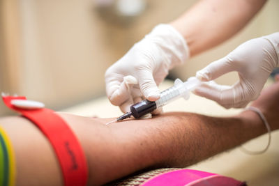 Cropped hands of doctor removing blood sample from patient arm