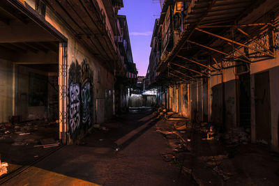 Footpath amidst abandoned building during sunset