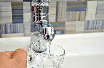 Cropped image of person filling water in glass