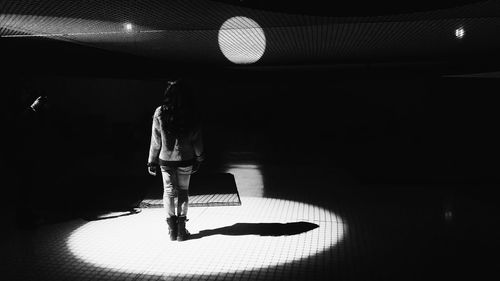 Rear view of woman standing in illuminated room