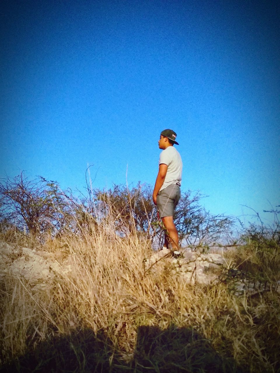 MAN STANDING ON FIELD AGAINST CLEAR SKY