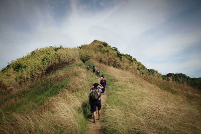 Rear view of people walking on mountain against sky