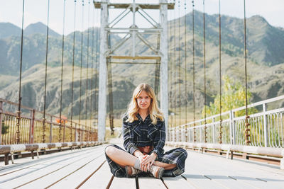 Portrait of young woman sitting on bridge