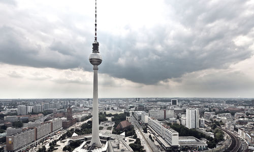 Fernsehturm and cityscape against cloudy sky