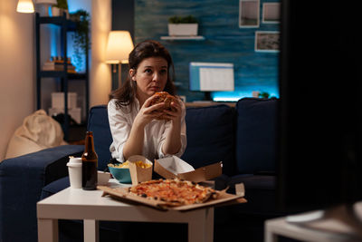 Portrait of young woman using mobile phone at restaurant