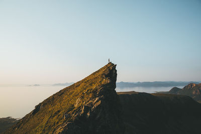 Mid distant view of man standing on cliff against sky