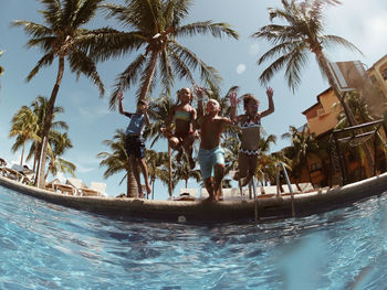 Low angle view of children jumping in swimming pool against sky