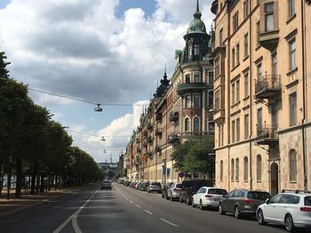 Cars on street amidst buildings in city against sky