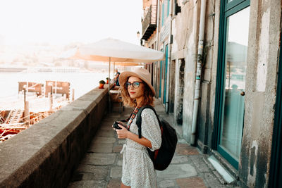 Side view of a young woman using camera in city