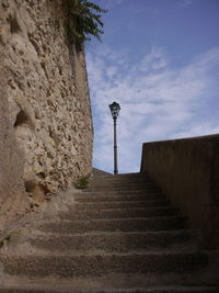 Low angle view of steps amidst wall against sky
