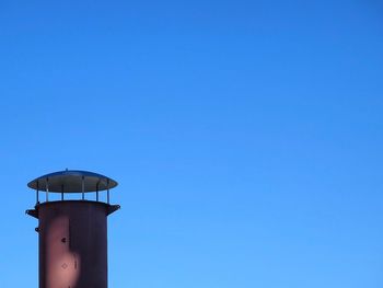 Low angle view of water tower against clear blue sky