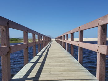 View of footbridge against clear blue sky