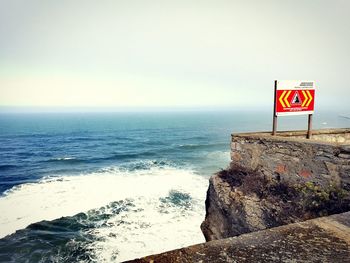 Road sign on beach against sky