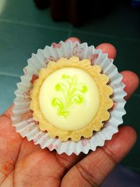 Close-up of smudge hand holding chesse tart with beautiful decoration