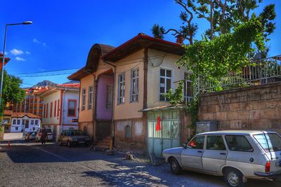 Cars on street by buildings against sky