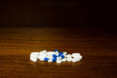 Simple pile of white and blue pills, medicines, pills stacked on brown background. medical supplies.