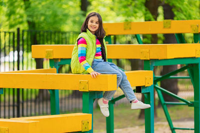 A cute smiling little girl, in a multi-colored striped jumper and a green vest