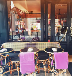 Empty chairs and tables at sidewalk cafe in city