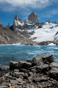 Scenic view of sea by snowcapped mountains against sky