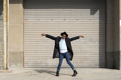 Full length of woman standing against wall