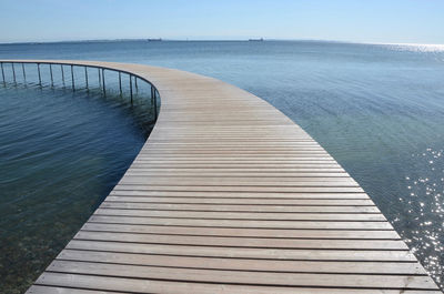 Boardwalk leading towards sea against sky