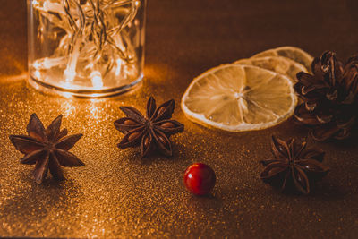 Star anises and orange slice by illuminated string lights