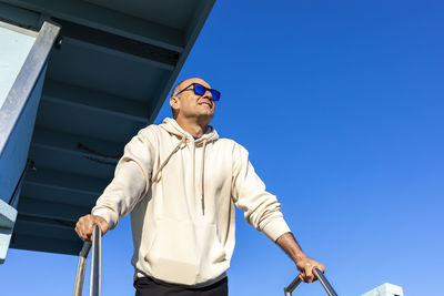 Low angle view of man standing against clear blue sky