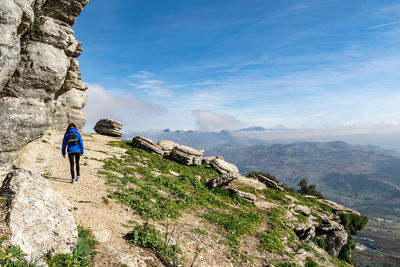 Full length of woman climbing on mountain against sky