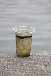 Mossy plastic cup beside the river