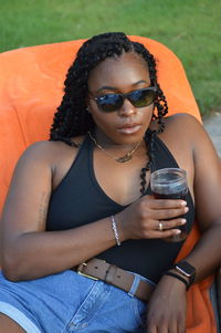 Portrait of woman having drink while siting on chair