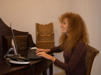 Smiling woman using computer at home