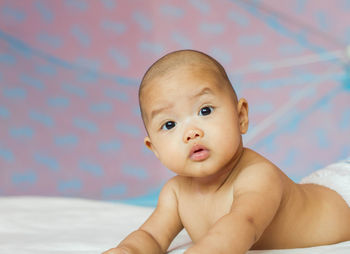 Portrait of cute baby lying on bed