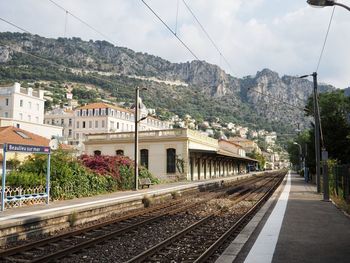 Railroad tracks by buildings in city against sky