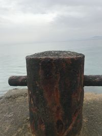 Close-up of rusty metal on beach against sky